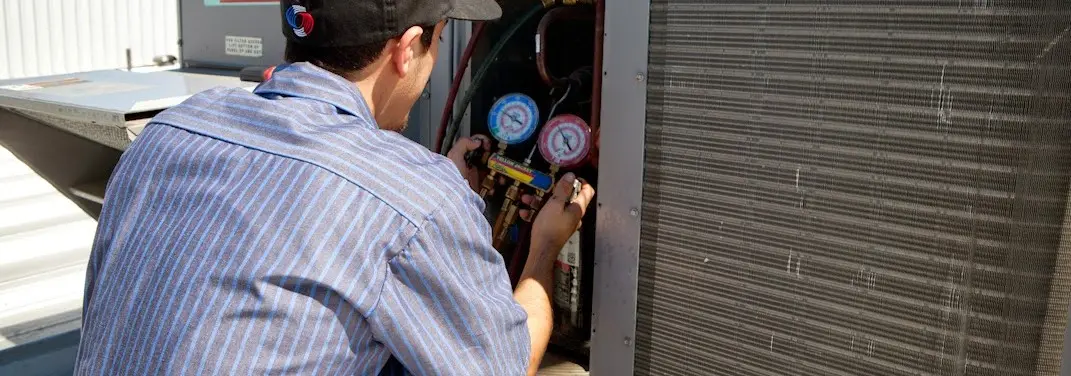 HVAC technician servicing a condenser unit in Nitro